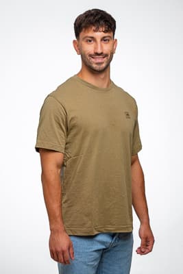 Pola plano americano Pola de plano americano de un actor sonriendo, vestido con camiseta verde y jeans en un estudio con fondo blanco.